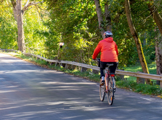 Person i röd jacka som cyklar på landsväg