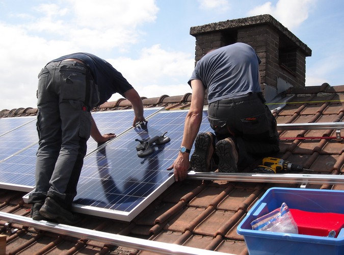 Två hantverkare monterar solpanel på tak