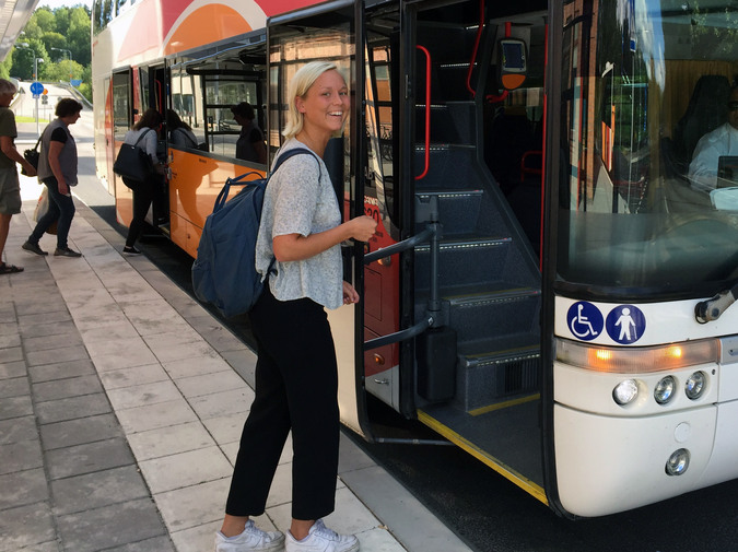 En glad tjej kliver på en buss.