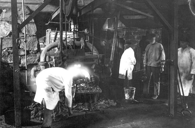 Färskning i Lancashirehärden i Häfla hammarsmedja. Bilden kan vara tagen i samband med att hammarsmedja utsågs till industriminne av Tekniska museet år 1934.