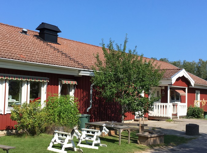 Björkhagens förskola. Ett rött envåningshus med gräsmatta och ett träd framför.