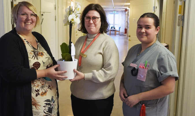 Socialrådet Frida Granath (S) överlämnar en blomma till enhetschef Annelie Olén och undersköterska Nathalie Karlsson.