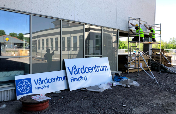 Bygget av Finspångs vårdcentrum i början av juni 2020. Uppsättning av skylt vid huvudentrén.